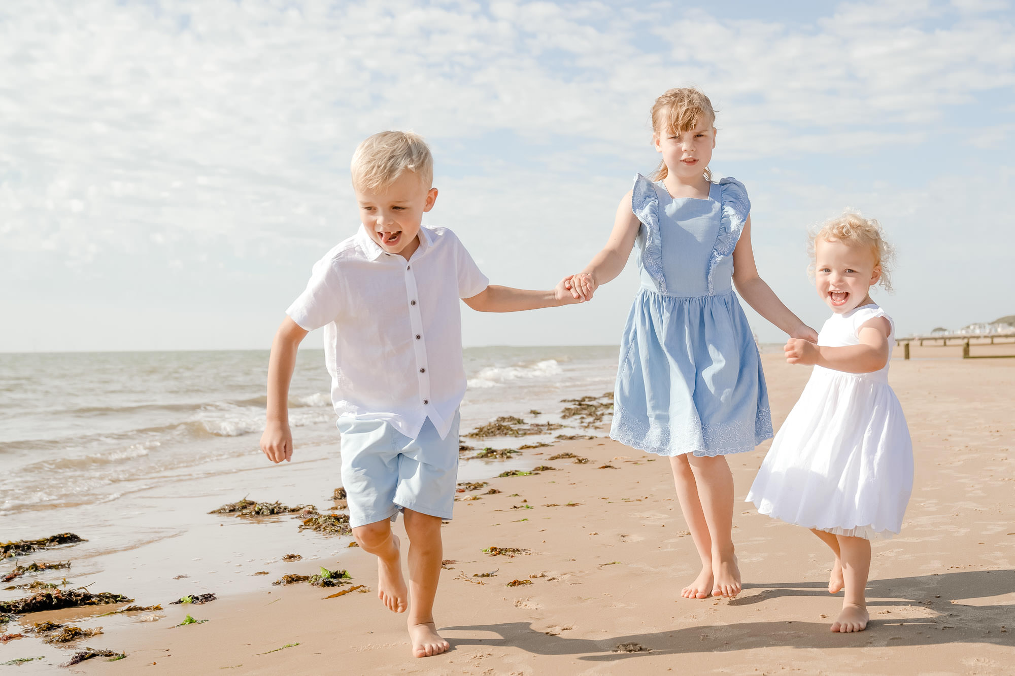 Children running on beach sand at family photography session near Colchester